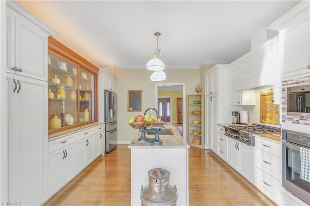 kitchen with light wood-style flooring, appliances with stainless steel finishes, an island with sink, and a sink