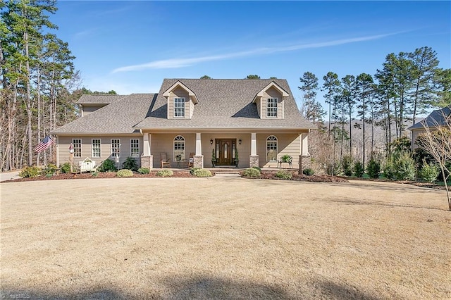 view of front of home featuring roof with shingles, a porch, and a front yard