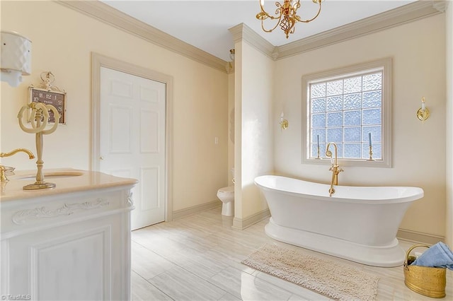 bathroom with toilet, a freestanding bath, ornamental molding, a notable chandelier, and a sink