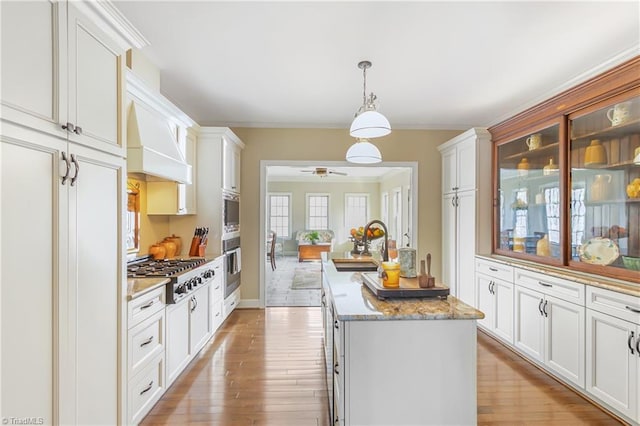 kitchen featuring a sink, stainless steel gas stovetop, light wood finished floors, and a center island