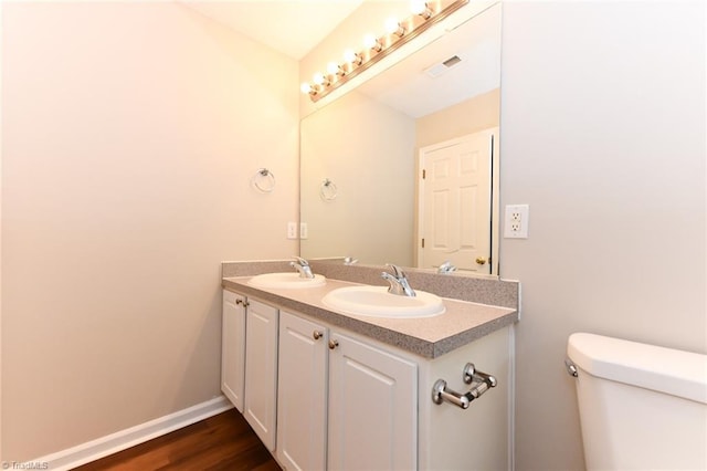 320 Apple Ridge Rd, Greensboro, NC 27406 - bathroom featuring toilet, double vanity, wood finished floors, and baseboards