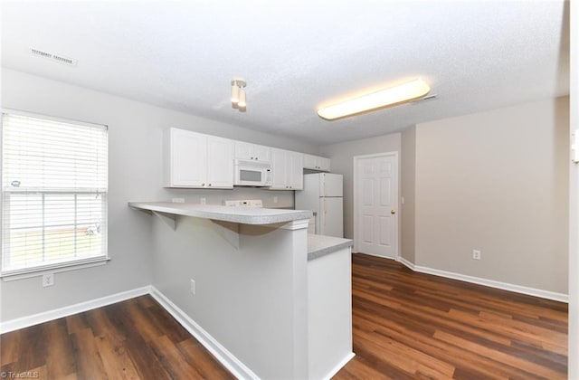 320 Apple Ridge Rd, Greensboro, NC 27406 - kitchen with white appliances, a peninsula, light countertops, white cabinets, and baseboards