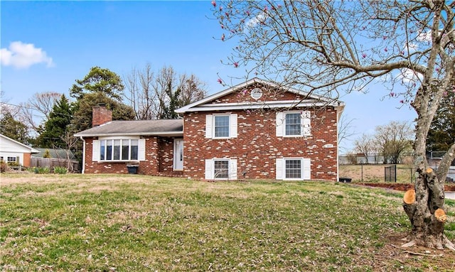 view of front of property with a front yard, brick siding, a chimney, and fence