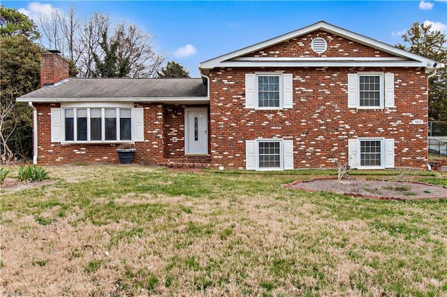 tri-level home featuring brick siding, a chimney, and a front lawn