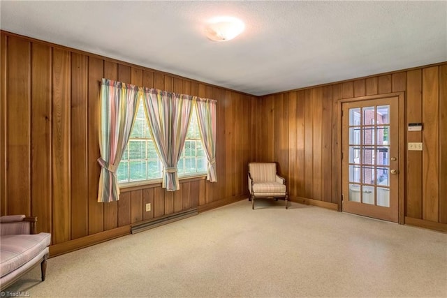 sitting room with wooden walls, plenty of natural light, and carpet