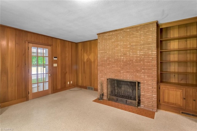 unfurnished living room featuring baseboards, a fireplace, wood walls, and visible vents