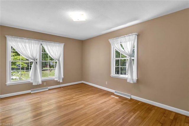 unfurnished room featuring baseboards, visible vents, and light wood-style floors