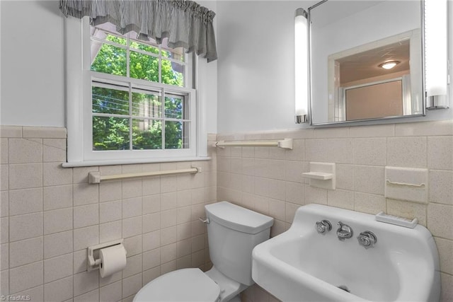 bathroom with a sink, tile walls, and toilet