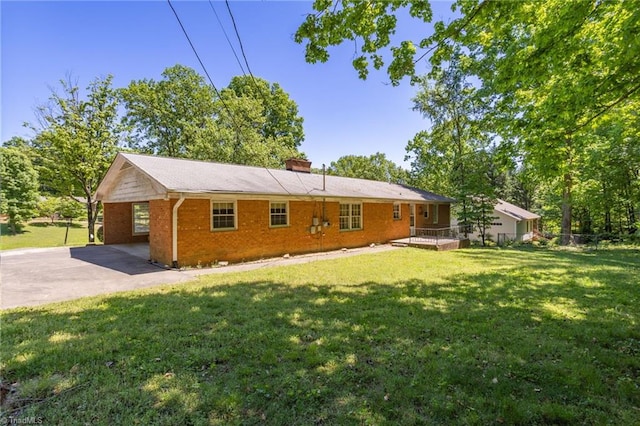 rear view of property featuring an attached carport, a yard, driveway, and brick siding