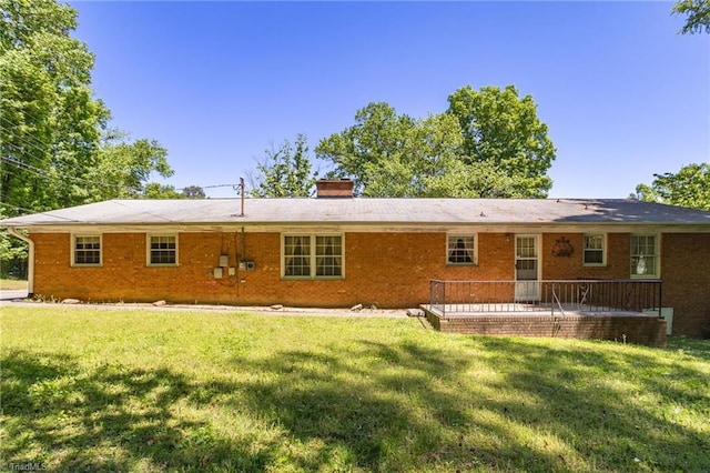 rear view of property featuring a patio, a chimney, a yard, and brick siding
