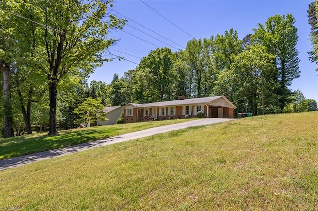single story home with a chimney, driveway, and a front yard