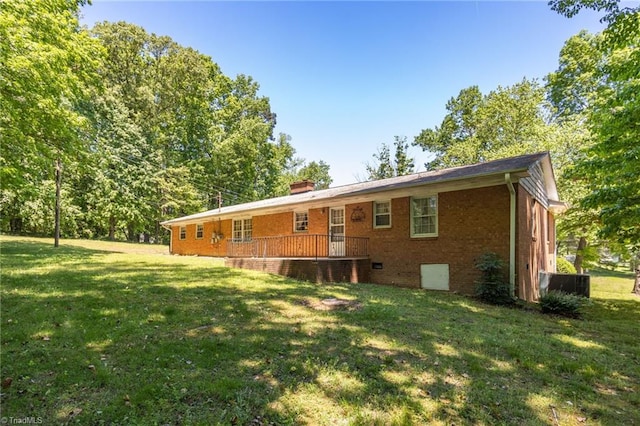 rear view of house with a lawn, central air condition unit, a chimney, and brick siding