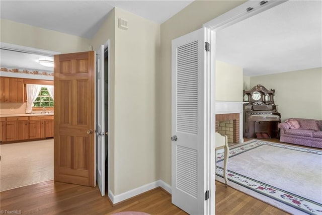 hallway featuring light wood-type flooring, a sink, and baseboards