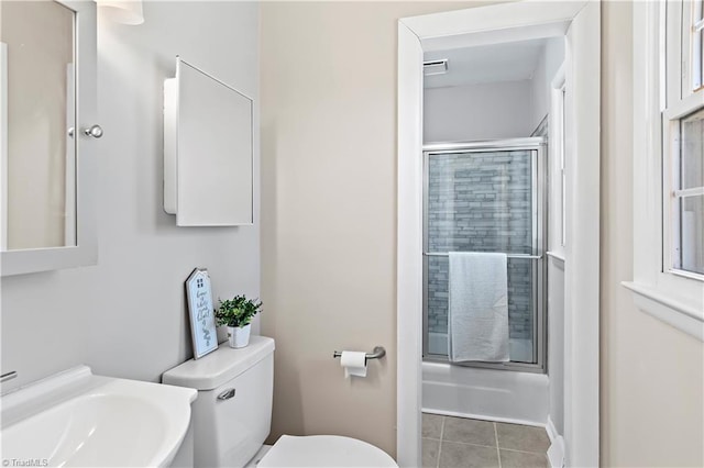 full bathroom featuring shower / bath combination with glass door, sink, toilet, and tile patterned flooring