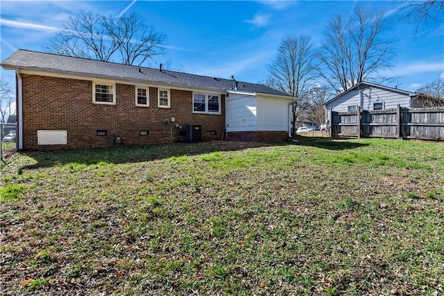 back of property with central AC and a lawn