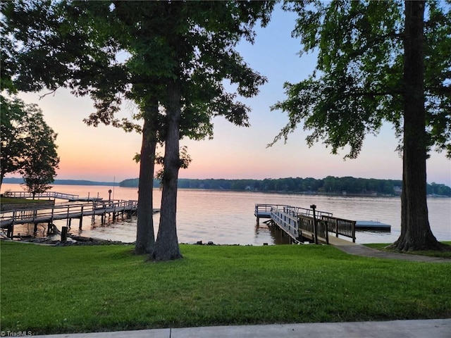 dock area with a lawn and a water view