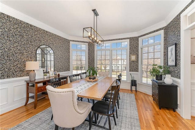 dining space featuring crown molding, plenty of natural light, wainscoting, and wallpapered walls