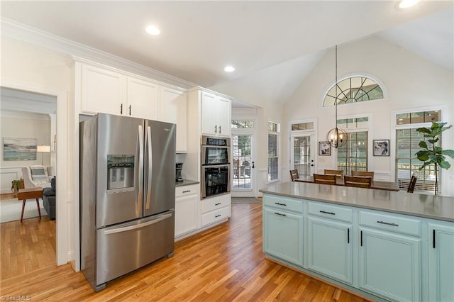 kitchen featuring light wood-style flooring, appliances with stainless steel finishes, white cabinets, and a notable chandelier