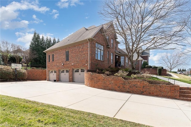 view of side of property with concrete driveway, brick siding, and an attached garage