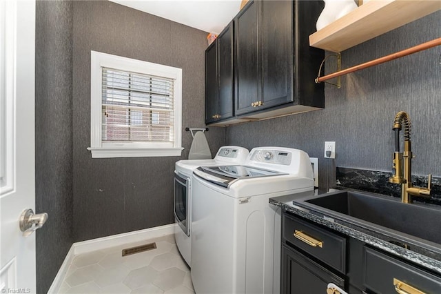 laundry area with washing machine and dryer, cabinet space, and a sink