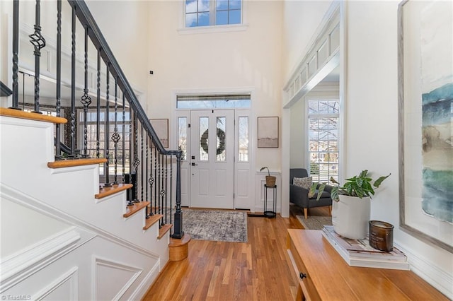 entryway with stairway, a towering ceiling, and wood finished floors