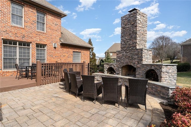 view of patio with an outdoor stone fireplace and outdoor dining area