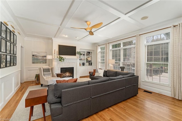 living room featuring visible vents, coffered ceiling, a wealth of natural light, and a decorative wall