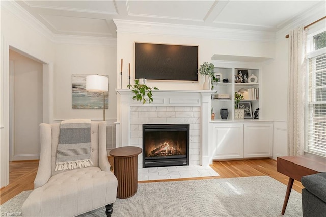 sitting room featuring built in features, light wood-style floors, ornamental molding, and a tiled fireplace