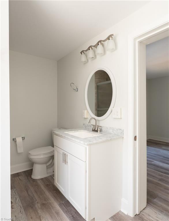 1473 Briarcliff Dr, Asheboro, NC 27205 - bathroom featuring baseboards, toilet, wood finished floors, and vanity