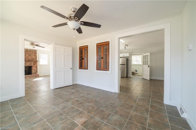 1473 Briarcliff Dr, Asheboro, NC 27205 - unfurnished room with dark tile patterned floors, baseboards, a brick fireplace, and ceiling fan