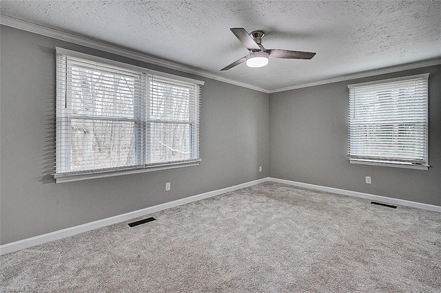 empty room featuring a textured ceiling, ceiling fan, crown molding, and carpet flooring