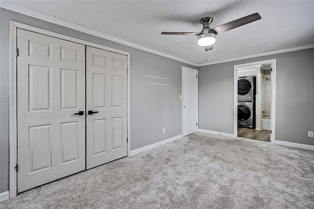 unfurnished bedroom with a textured ceiling, light carpet, ceiling fan, a closet, and stacked washer and dryer