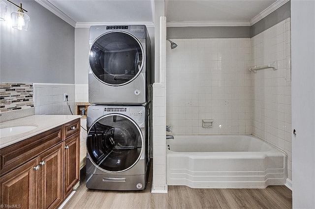 laundry room with ornamental molding, light hardwood / wood-style flooring, stacked washer / dryer, and sink