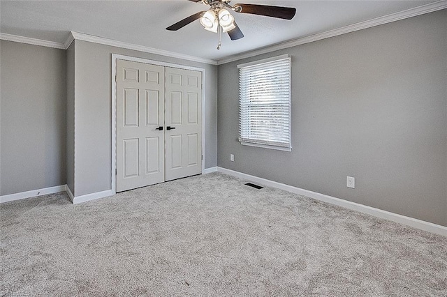 unfurnished bedroom featuring ceiling fan, light colored carpet, ornamental molding, and a closet