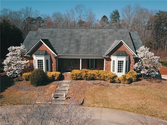 view of front of house with brick siding and roof with shingles