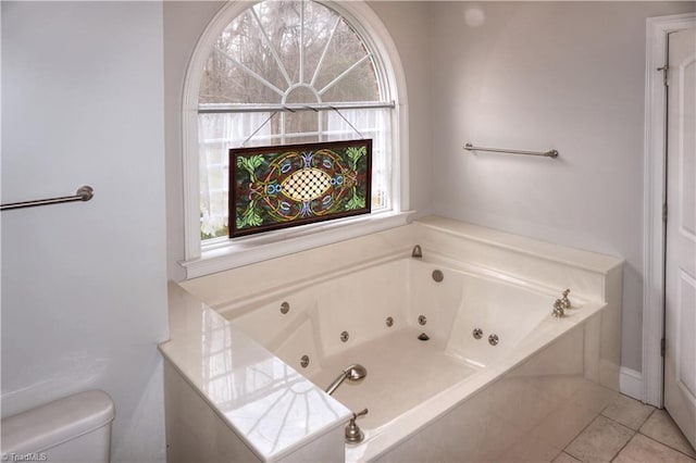 full bathroom with tile patterned floors, a jetted tub, and toilet