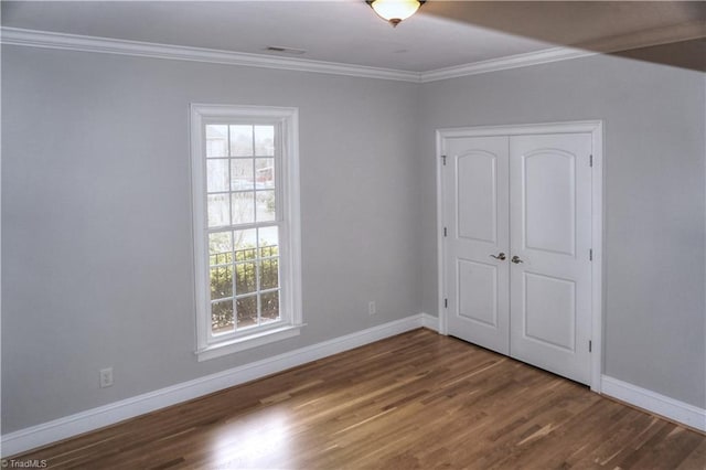 unfurnished bedroom featuring multiple windows, crown molding, and wood finished floors