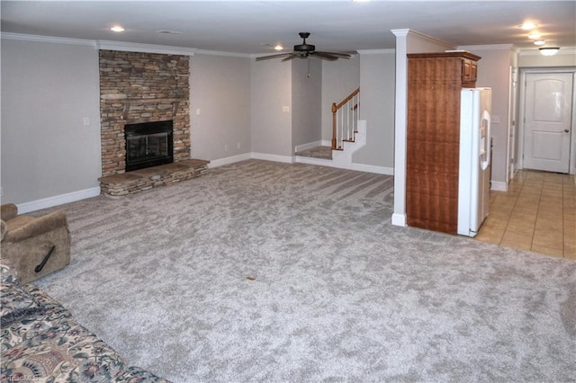 unfurnished living room with a stone fireplace, stairway, light colored carpet, and ornamental molding