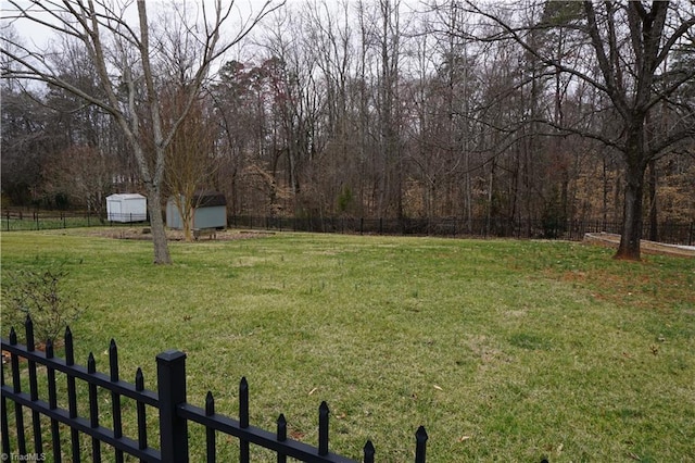 view of yard with a shed, an outdoor structure, and fence