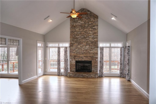 unfurnished living room featuring ceiling fan, visible vents, a stone fireplace, and wood finished floors