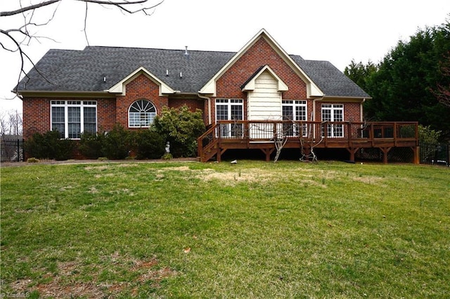 back of property with a deck, a yard, and brick siding