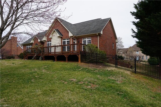 back of property featuring a yard, fence, brick siding, and a wooden deck