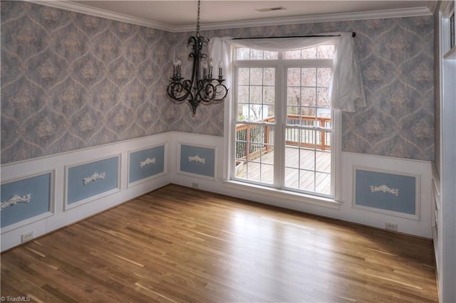 unfurnished dining area featuring visible vents, wallpapered walls, crown molding, and wood finished floors