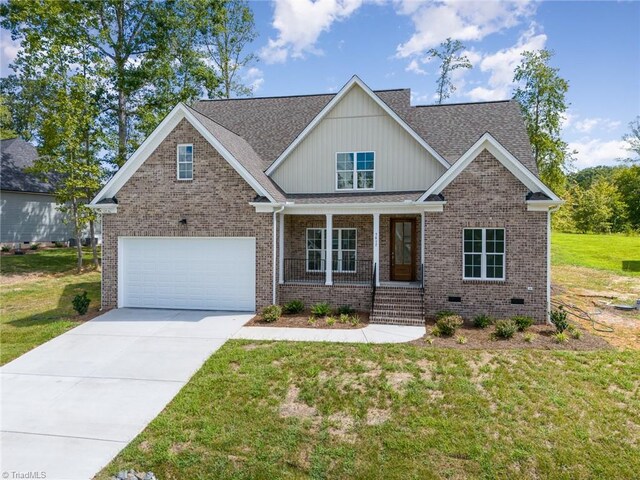 craftsman house with covered porch, a front yard, and a garage