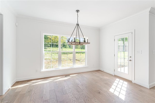 unfurnished dining area with a chandelier, a wealth of natural light, light hardwood / wood-style floors, and ornamental molding