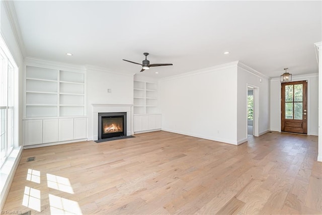 unfurnished living room featuring crown molding, a fireplace with flush hearth, and light wood-style floors
