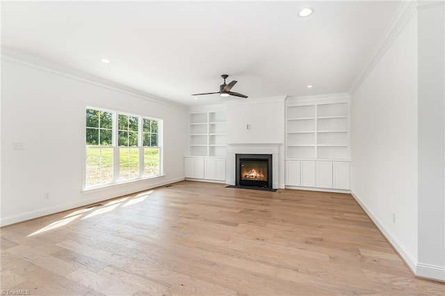 unfurnished living room with light wood-type flooring, built in features, ceiling fan, and crown molding