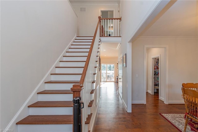 stairs with hardwood / wood-style flooring and ornamental molding