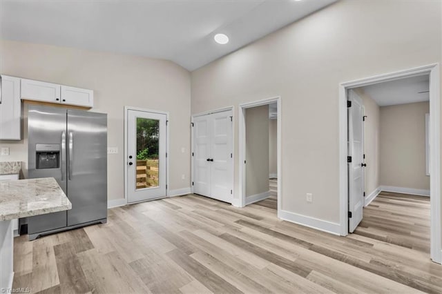 3077 Little Creek Dr, Thomasville, NC 27360 - kitchen featuring stainless steel refrigerator with ice dispenser, light wood finished floors, white cabinetry, light stone countertops, and lofted ceiling