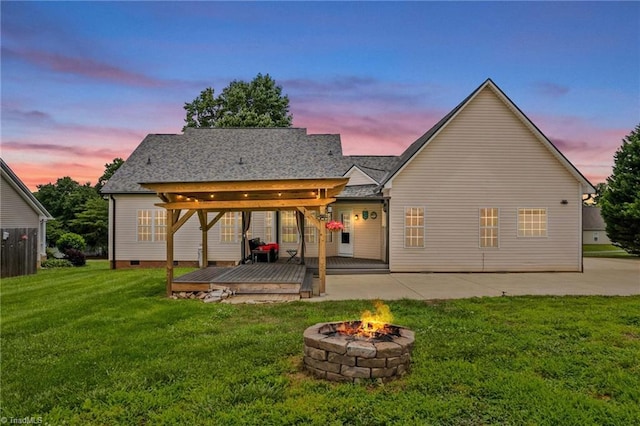 159 Forest Abbey Ln, China Grove, NC 28023 - back of house at dusk featuring an outdoor fire pit, a wooden deck, a lawn, a patio area, and crawl space